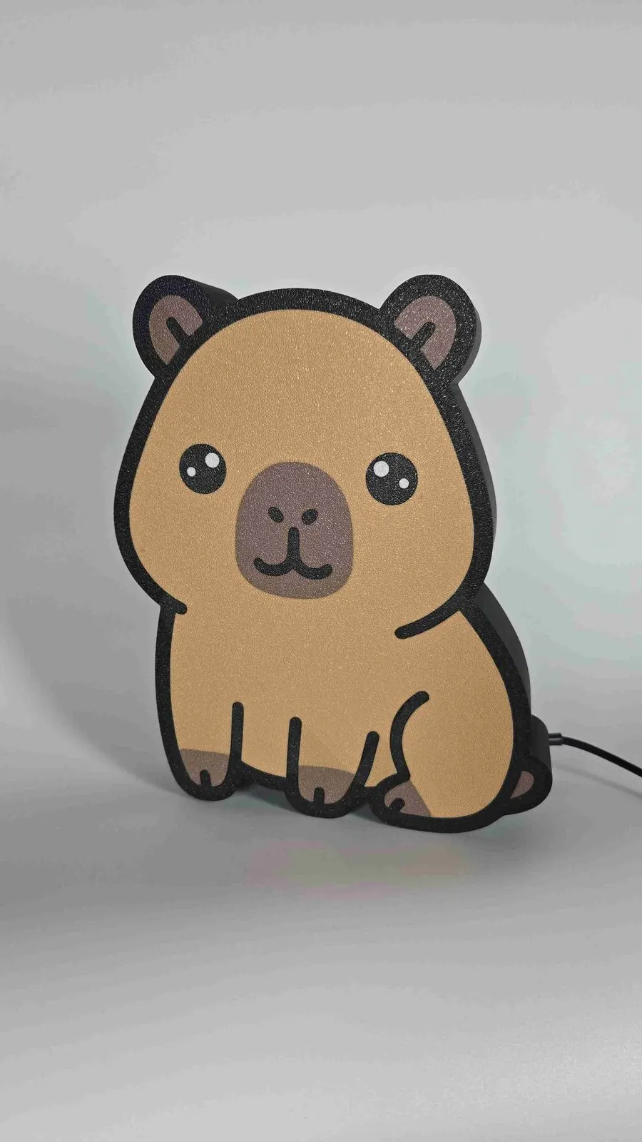 Lampe DEL décorative en forme de capybara imprimée en 3D, allumée sur un meuble